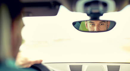Image showing rearview mirror reflection of man driving car