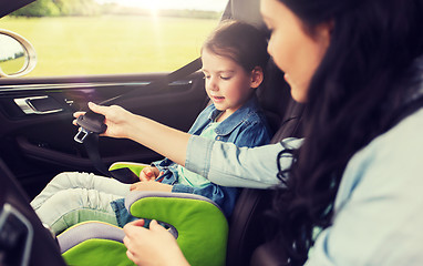 Image showing happy woman fastening child with seat belt in car