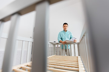 Image showing father with manual assembling baby bed at home