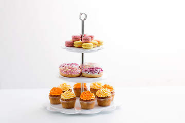 Image showing glazed donuts, cupcakes and macarons on stand