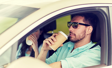 Image showing happy man and woman driving in car with coffee