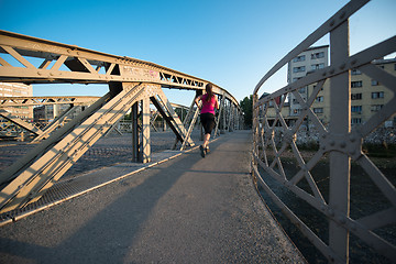 Image showing woman jogging across the bridge at sunny morning