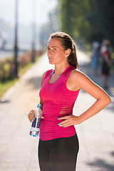 Image showing woman drinking water from a bottle after jogging