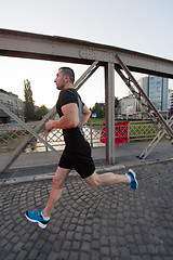 Image showing man jogging across the bridge at sunny morning