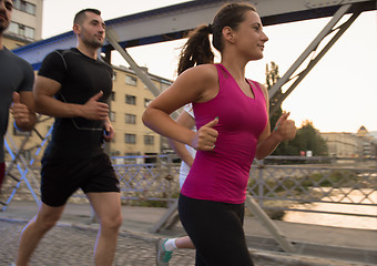 Image showing group of young people jogging across the bridge