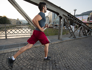 Image showing man jogging across the bridge at sunny morning