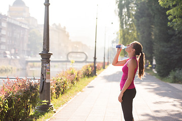 Image showing woman drinking water from a bottle after jogging