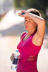 Image showing woman drinking water from a bottle after jogging