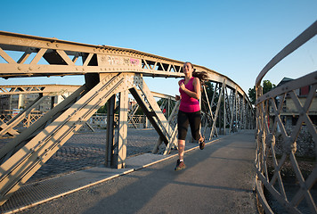 Image showing woman jogging across the bridge at sunny morning