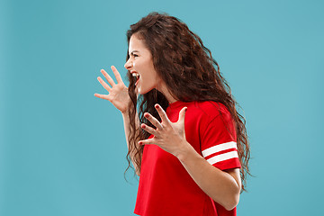 Image showing The young emotional angry woman screaming on blue studio background