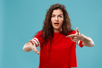 Image showing Beautiful female half-length portrait isolated on blue studio backgroud. The young emotional surprised woman