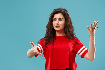 Image showing Beautiful female half-length portrait isolated on blue studio backgroud. The young emotional surprised woman