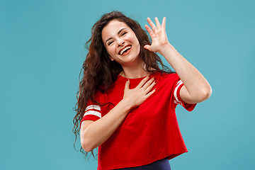 Image showing Beautiful female half-length portrait isolated on blue studio backgroud. The young emotional surprised woman