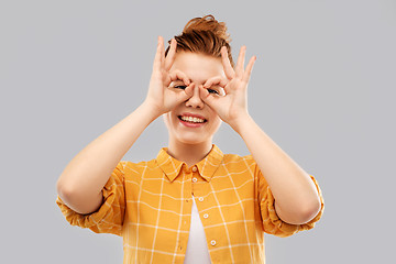 Image showing red haired teenage girl making finger glasses