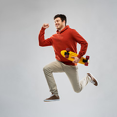 Image showing smiling young man in hoodie with short skateboard