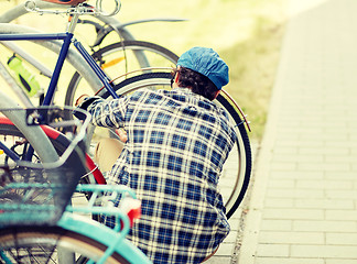 Image showing man fastening bicycle lock on street parking