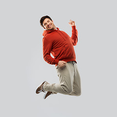 Image showing young man in hoodie jumping over grey background