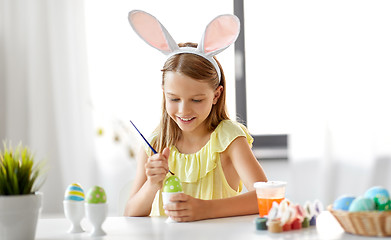 Image showing happy girl coloring easter eggs at home