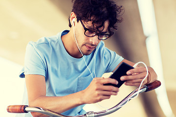 Image showing man with smartphone and earphones on bicycle