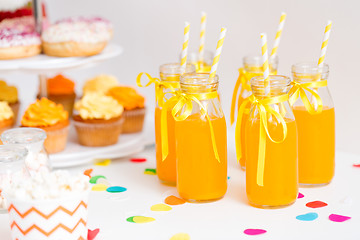 Image showing orange juice in glass bottles with paper straws