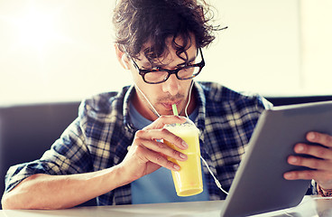 Image showing man with tablet pc and earphones sitting at cafe