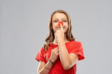 Image showing smiling teenage girl with red clown nose