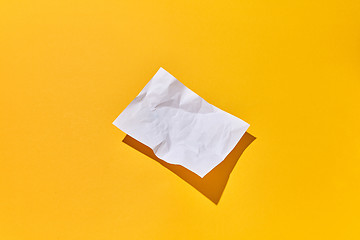 Image showing Crumpled paper sheet with hard shadows on an yellow background.