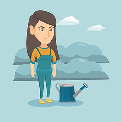 Image showing Young farmer standing in a field with watering can