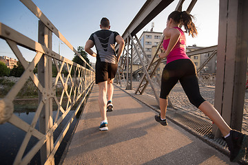 Image showing young couple jogging across the bridge in the city