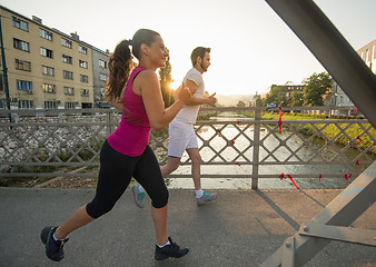 Image showing young couple jogging across the bridge in the city