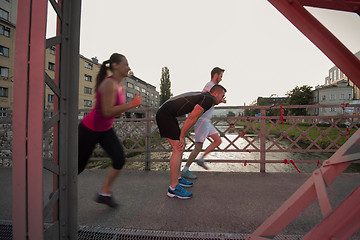 Image showing group of young people jogging across the bridge