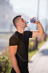 Image showing man drinking water from a bottle after jogging