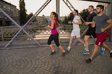 Image showing group of young people jogging across the bridge