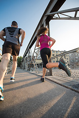 Image showing young couple jogging across the bridge in the city