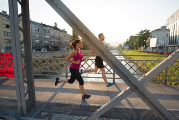 Image showing young couple jogging across the bridge in the city