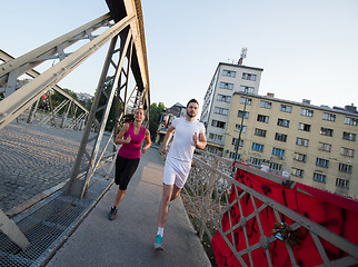 Image showing young couple jogging across the bridge in the city