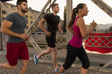 Image showing group of young people jogging across the bridge