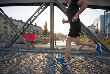 Image showing man jogging across the bridge at sunny morning