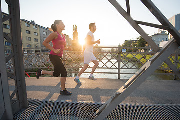 Image showing young couple jogging across the bridge in the city