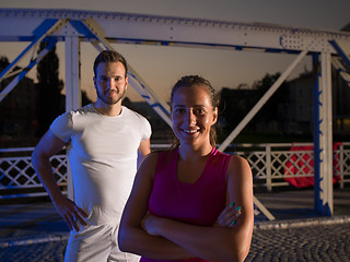 Image showing portrait of couple jogging across the bridge in the city
