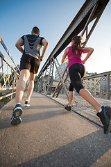 Image showing young couple jogging across the bridge in the city