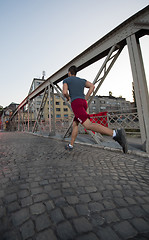 Image showing man jogging across the bridge at sunny morning