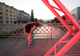 Image showing man jogging across the bridge at sunny morning