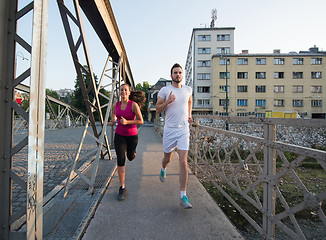 Image showing young couple jogging across the bridge in the city