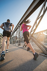 Image showing young couple jogging across the bridge in the city