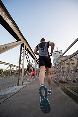 Image showing man jogging across the bridge at sunny morning