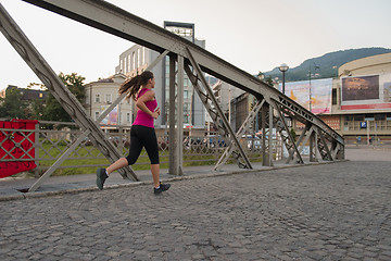 Image showing woman jogging across the bridge at sunny morning