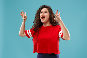 Image showing The young emotional angry woman screaming on blue studio background