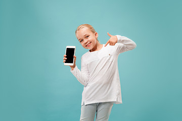 Image showing The happy teen girl standing and smiling against blue background.