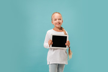 Image showing Little funny girl with tablet on blue background